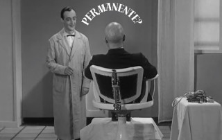 > Scena satirica dal barbiere con rasatura completa del capo e barba alla balbo, citazione della figura di Mussolini e la scritta "permanente"